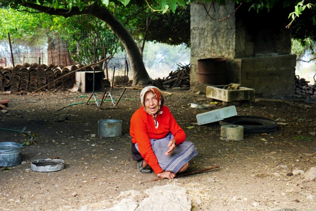 An elderly woman sits in the yard of her house during a wildfire, Neochori, Gortynia, August, 2021.